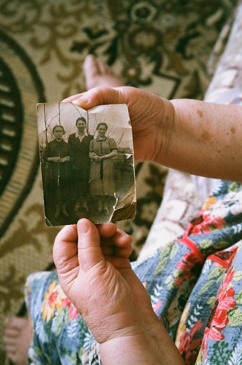 Elderly hands carefully holding a vintage family photo, evoking memories and the importance of preservation