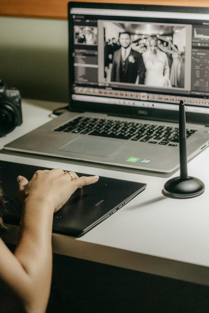 Professional photo editor using graphics tablet and stylus to retouch photographs on calibrated monitor at dedicated workstation