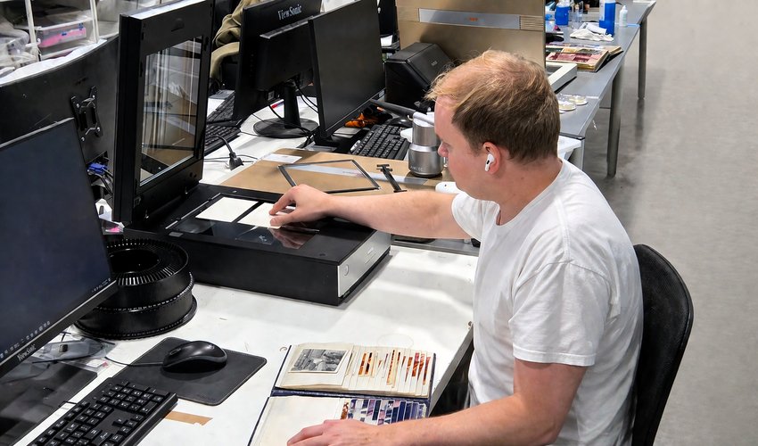 Technician scanning a family photo on a professional flatbed scanner at Forever Studios
