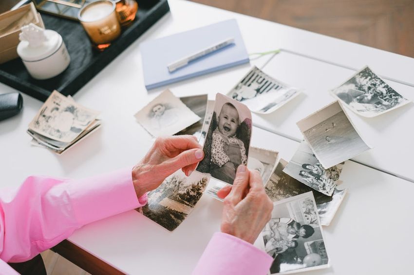 Person carefully sorting and organizing old black and white family photos on a table for scanning