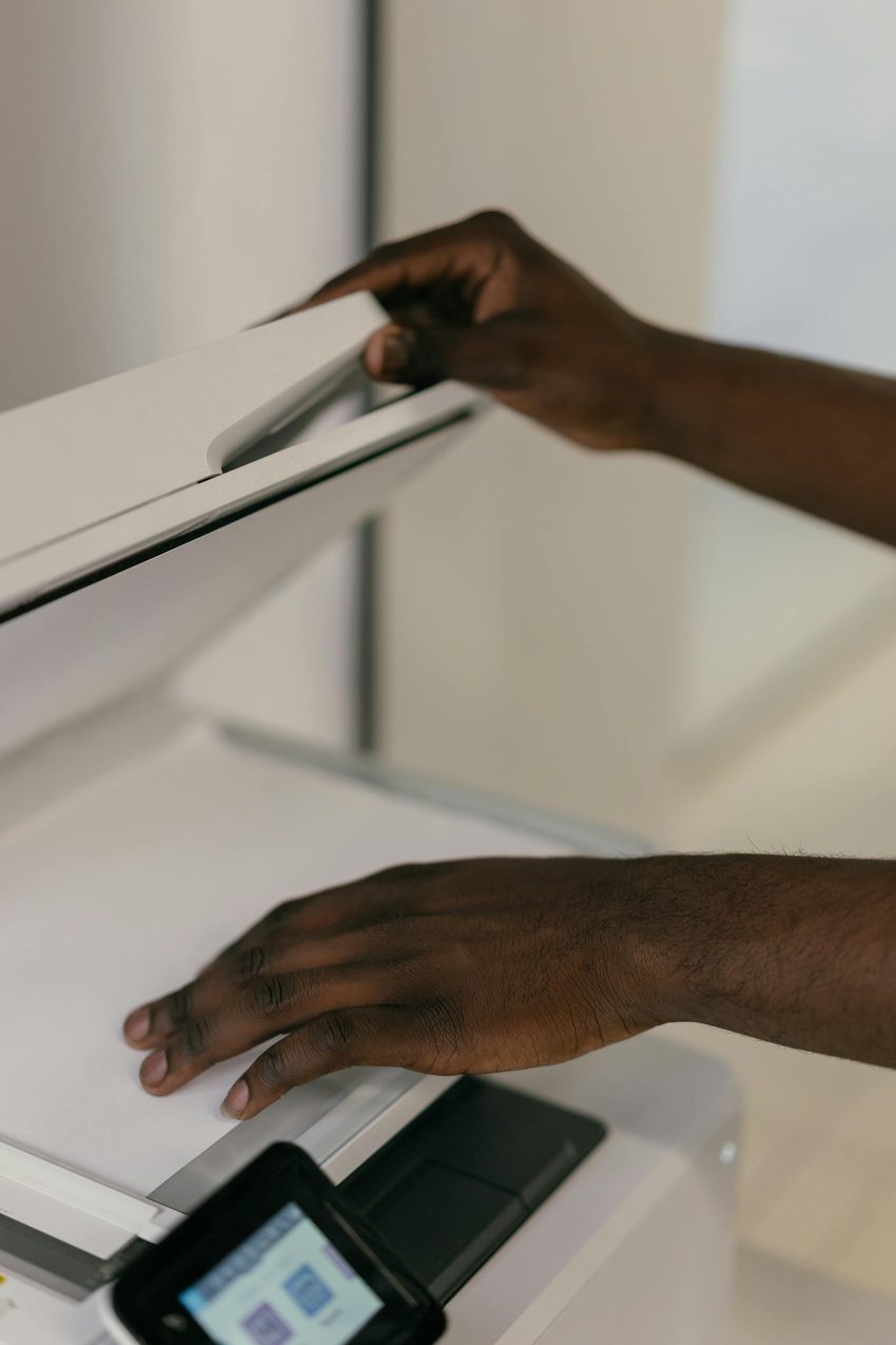 Hands carefully adjusting a document on a professional flatbed scanner, the same careful process used when scanning irreplaceable original photographs