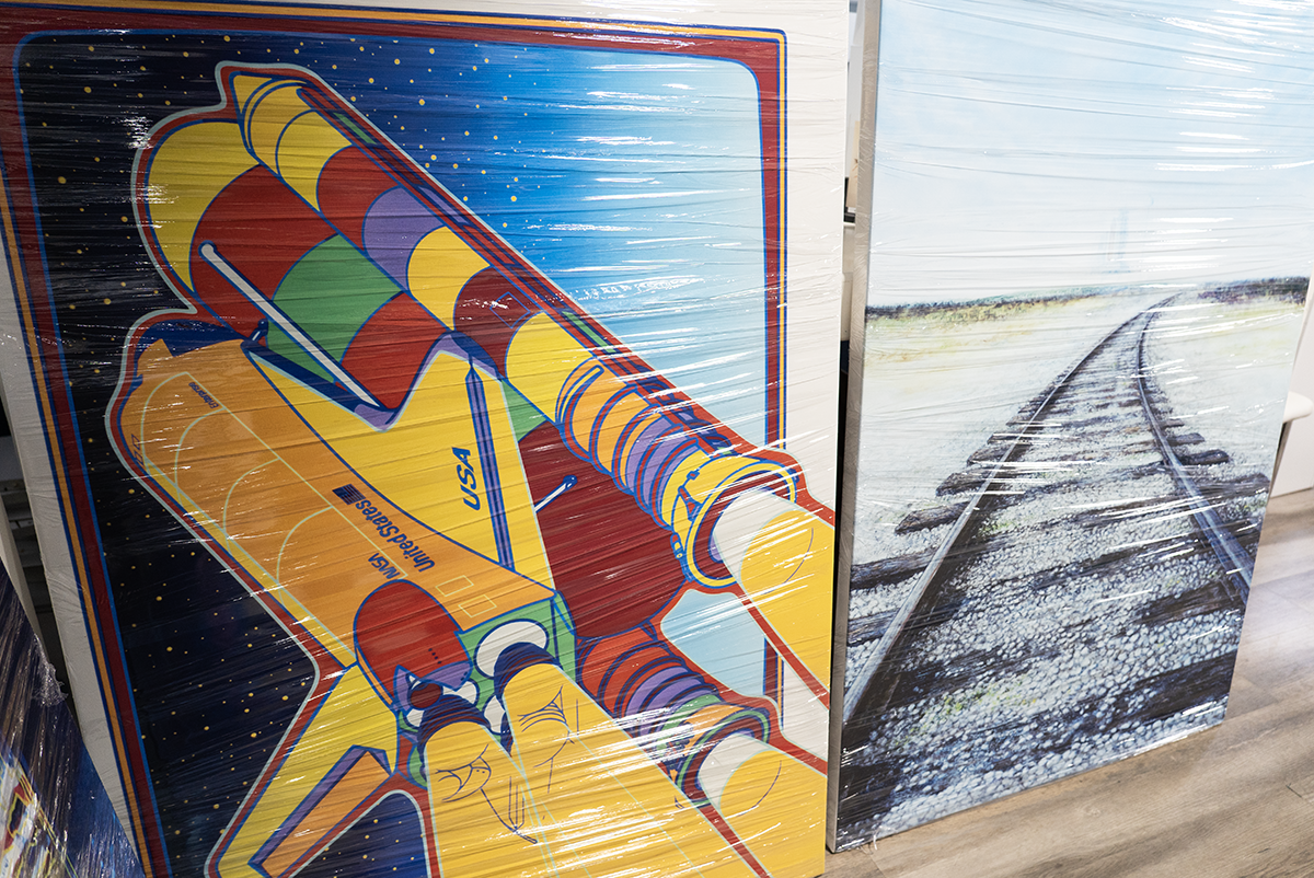 Multiple restored NASA artwork prints laid out for final inspection before delivery