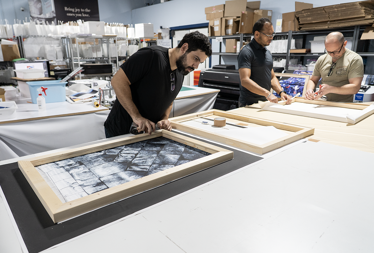 Forever Studios team members Emilio Swamy and Shawn preparing artwork for delivery